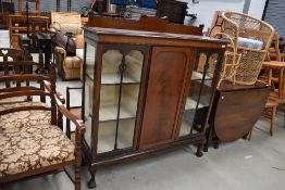 An early 20th Century mahogany display cabinet having ledge back, central cupboard flanked by