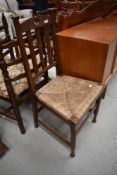An early 20th Century oak chair having rush seat, in the Arts and Crafts style with heart motif to