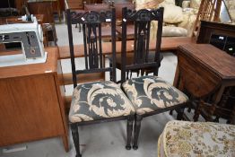 A pair of late 19th dark stained dining chairs with overstuffed seats having later upholstery,