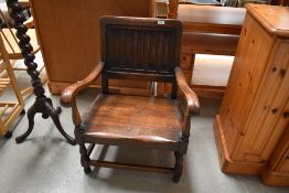 A traditional dark oak low seat carver chair having solid seat , scroll arms and carved back