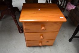 A modern pine bedside chest of three drawers