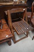A folding garden chair and stained frame magazine rack