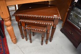 A reproduction hardwood nest of three occasional tables having fluted legs