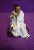 A vintage Chinese figure of a man playing instrument in a mudman style signed Wan Jiang to base