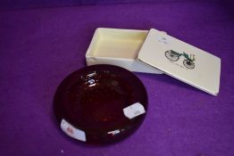 A ruby red control bubble glass dish and ceramic lidded container with transport imagery