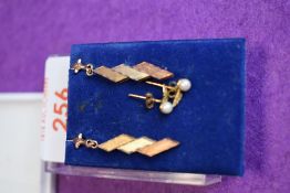 A pair of three coloured yellow metal stud earrings bearing worn marks to posts and a pair of yellow