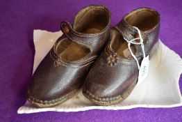 A pair of antique child shoes or clogs with leather body and wooden sole with wood worm