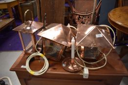 Three copper wall lights, lantern style, and a pair of copper candlesticks