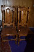 A set of four traditional oak colonial style dining chairs having panel backs and solid seats