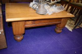 A light stained coffee table, on heavy legs