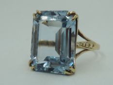 A lady's over sized dress ring having a large blue synthetic stone in a claw set basket mount on a