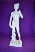 A classically styled nude figure of gent leaning against log or Michaelangelo's David.