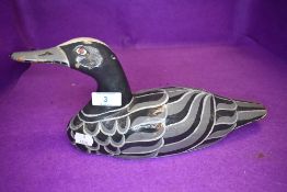 An early 20th century wooden carved hunting duck or bird decoy painted grey and black