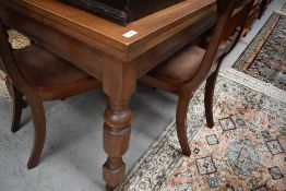 An Edwardian fold out oak table on turned legs