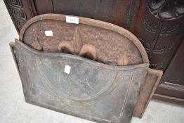 A vintage cast iron fireback with fleur de lys decoration and a cast canopy