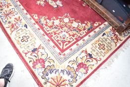 A traditional room sized carpet square, having red ground and floral vase pattern