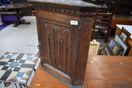 A small oak corner cupboard having a religious style