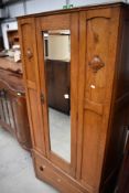 An early 20th Century golden oak wardrobe having single mirror door