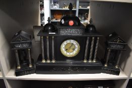 A slate mantel clock with matching garnitures