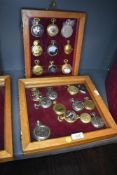 Two glazed display cases containing twenty one pocket watches or time pieces