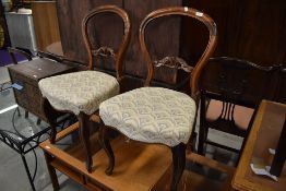 A pair of balloon back rose wood dining chairs with carved detailing