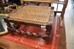 A Victorian carved mahogany footstool having bergere top and barley twist frame