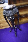 An Oriental hardwood plant stand having rouge marble inlay
