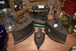 Five antique flat top stove irons including miniature iron with trivet