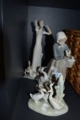Three bisque glazed figure studies including girl feeding ducks by Lladro