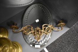 A wall mounted double bracket candle stick and an oval hall way mirror having bullseye decoration on
