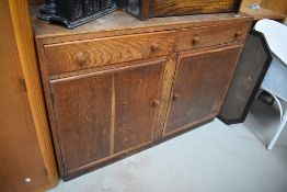 A late Edwardian oak utility or kitchen cupboard dresser base