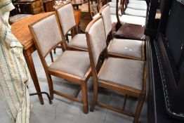A set of four early 20th Century oak dining chairs having late upholstered seats (with fire labels)