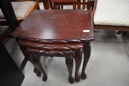 A reproduction mahogany effect nest of three tables