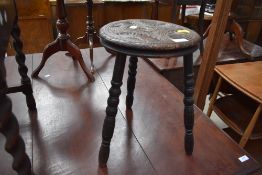 A traditional carved oak milking style stool, having three turned legs, probably 19th Century
