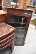An Edwardian corner cupboard having rolled glass front