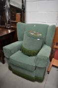 A vintage wingback armchair and woolwork top footstool