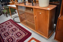 A Priory golden oak slim bookcase having glazed section and cupboard, on shepherds casters, width
