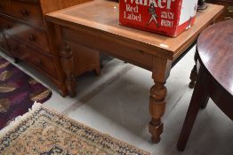 An Edwardian fold out oak table on turned legs