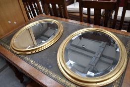 A pair of reproduction distressed gilt effect oval wall mirror