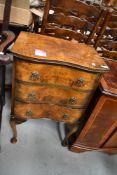An early 20th Century walnut serpentine chest of three bedside or similar drawers on cabriole