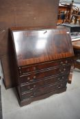 A modern dark stained bureau having four under drawer