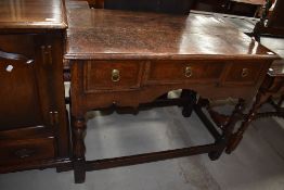 A period oak side table having three drawers, shaped apron, turned legs and plain supports to four