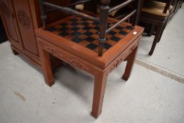 An Oriental hardwood games table, having chess board top and pieces to drawer