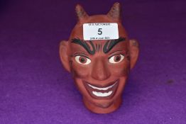 A ceramic puppet or similar toy head in the form of a Devil