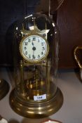 A vintage brass anniversary clock having glass dome and enamel face.