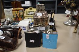 A vintage cocktail shaker and a selection of hip flasks.