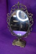 A vintage brass bodied mirror having scroll work frame