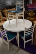 A mid century circular dining table having set of four teal seated ladder back chairs