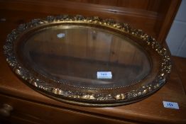 A modern oval framed mirror having carved gilt frame and bevel edged glass