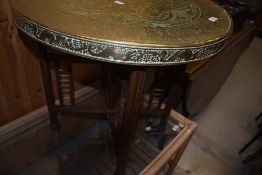 A Chinese brass top table having folding stained frame base